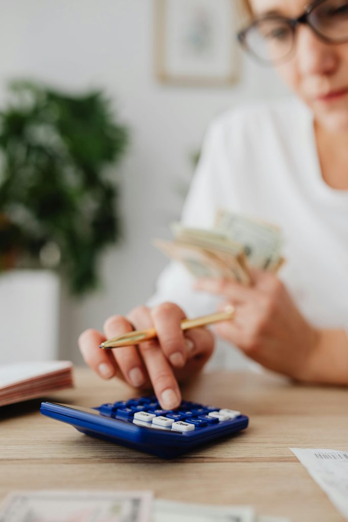 A woman uses a calculator and holds money, illustrating personal finance management.