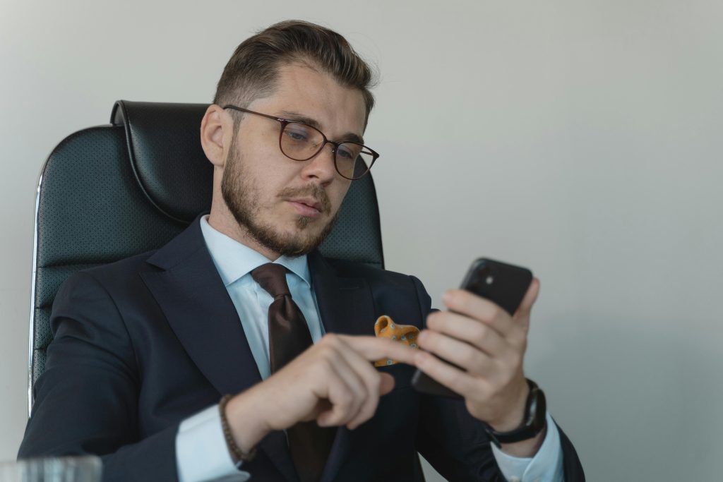 Professional businessman in a formal suit using his smartphone in an office setting.