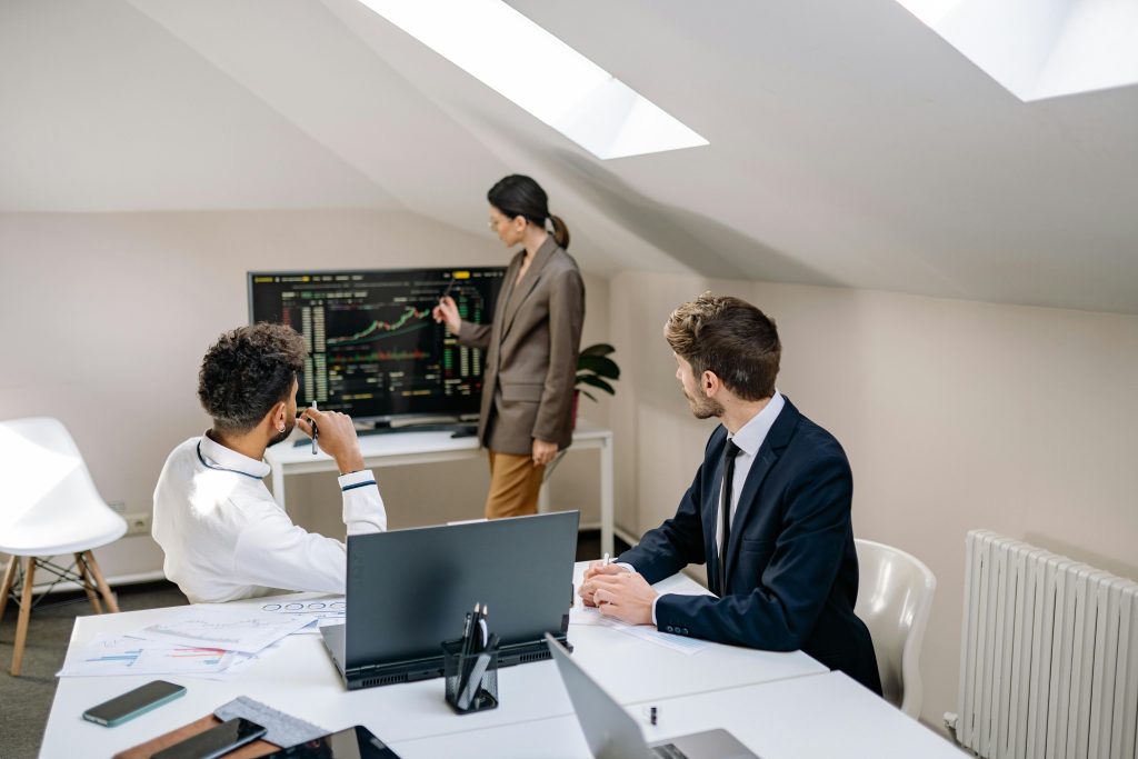 Professionals discussing stock market trends with charts in an office setting.