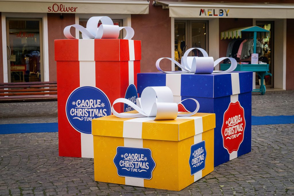 Vibrant oversized gift boxes in an outdoor shopping area, perfect for holiday themes.