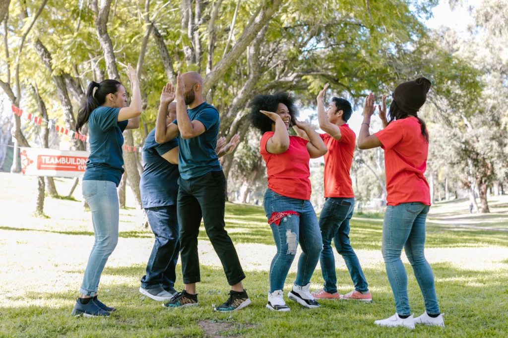 Diverse group of adults enjoying an energetic team building activity in a sunny park.